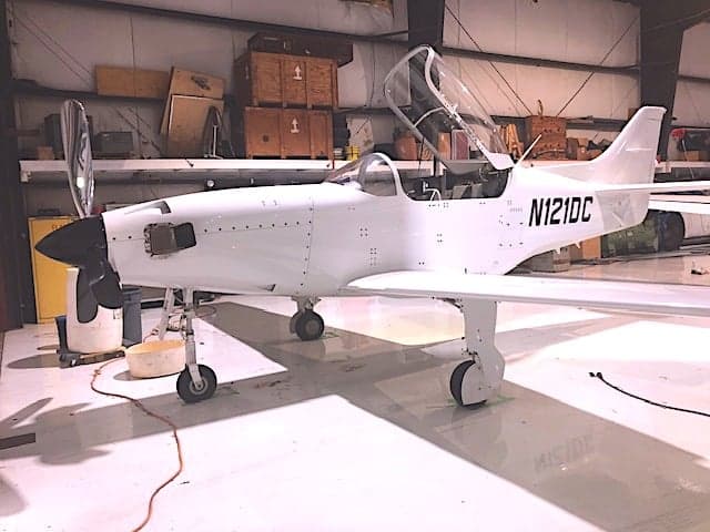 A white aircraft with tail number N121DC is parked in a hangar.