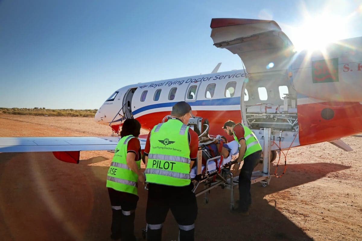 Medical personnel loading a patient into a Royal Flying Doctor Service Pilatus PC-24 aircraft.