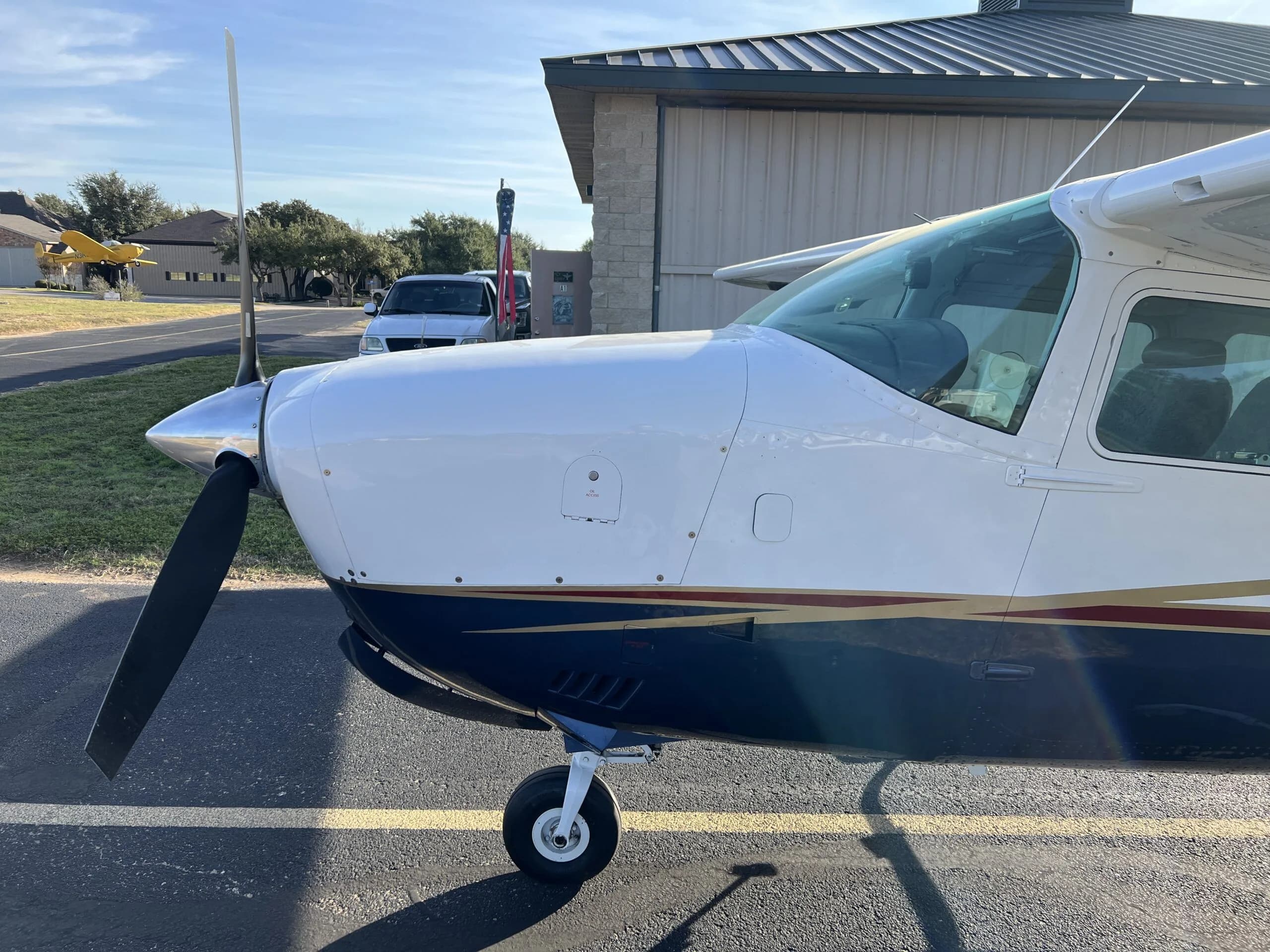 A close-up side view of the front fuselage and propeller of the white and blue Cessna 210, N58MA.