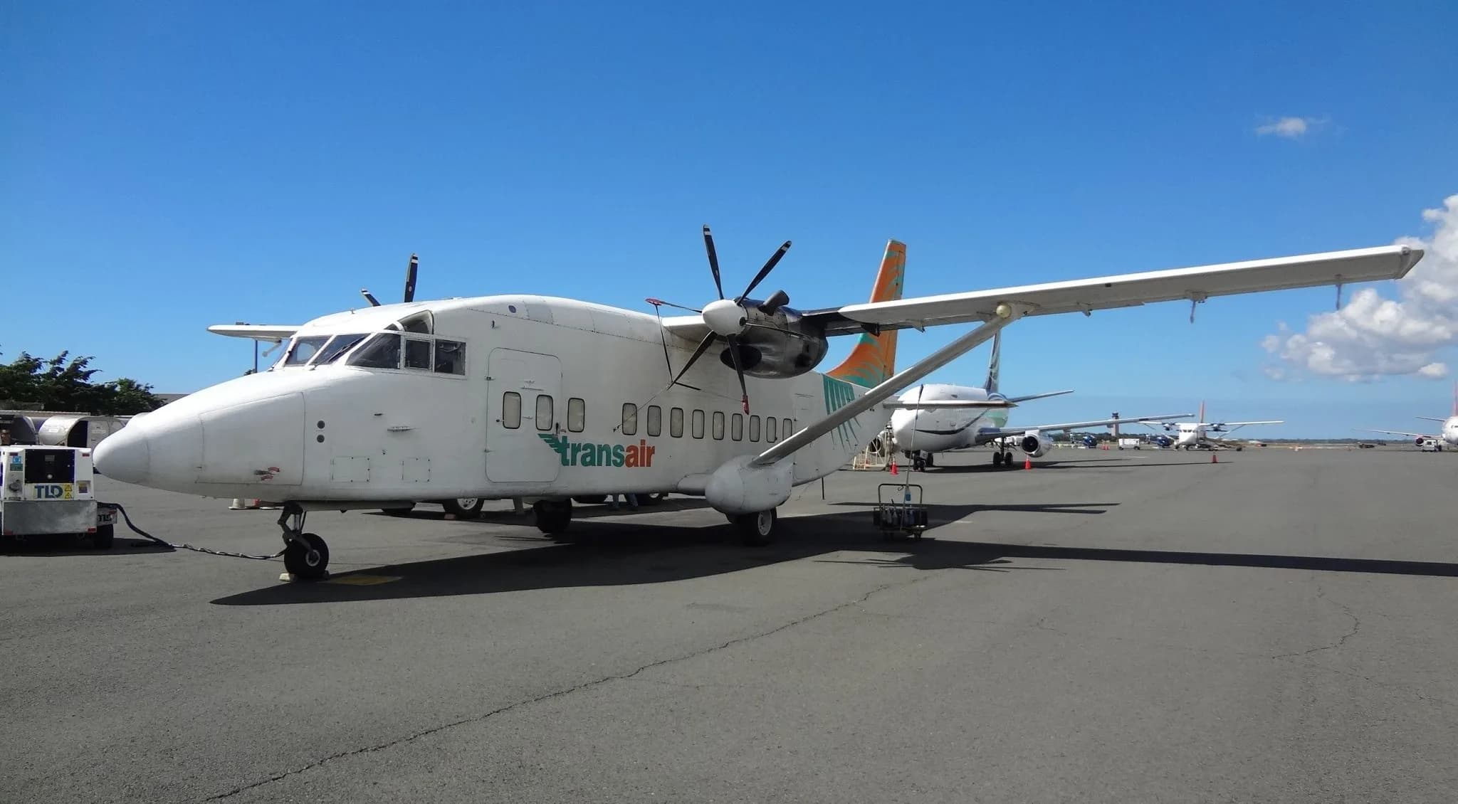 A Transair aircraft is parked on the tarmac at an airport.