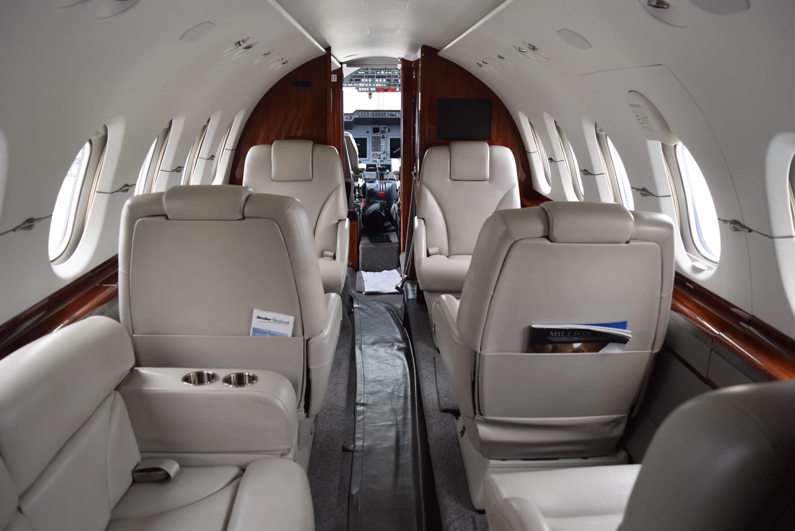 View of the aircraft cabin with cream-colored leather seats and wood trim.