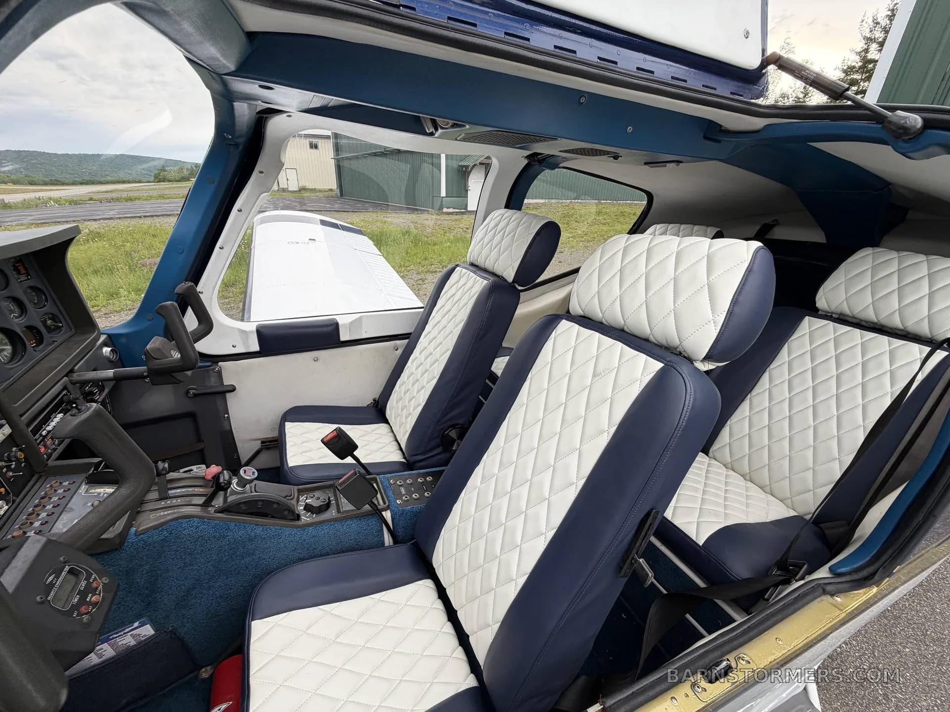 The interior of a Socata Trinidad TB20 showing blue and white quilted leather seats and part of the cockpit.