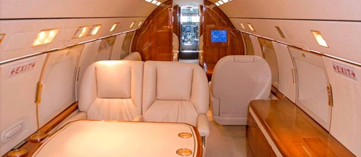 Interior of the aircraft with cream-colored seats and wood accents.