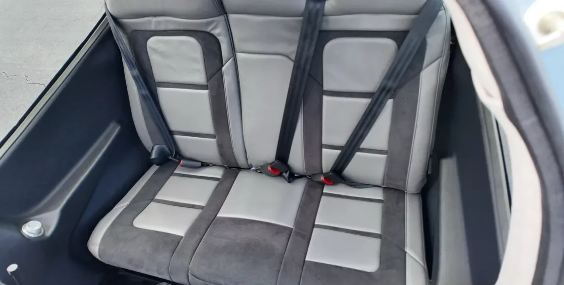 An overhead view of the gray and dark gray rear passenger seats with seatbelts in an aircraft cabin.