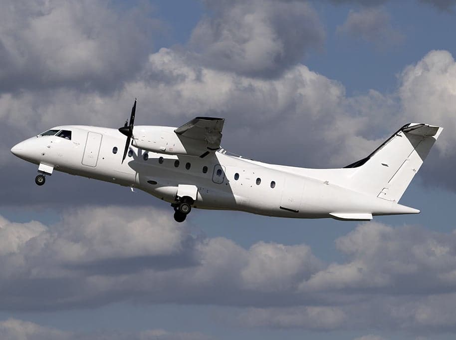 A white turboprop aircraft is shown in flight against a cloudy sky.