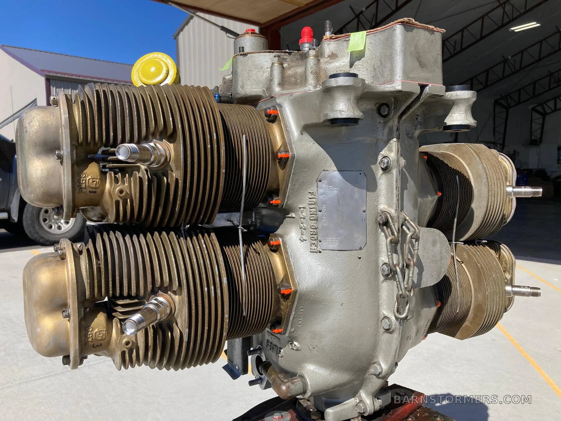 A grey aircraft engine with a data plate visible, outdoors near a hangar.