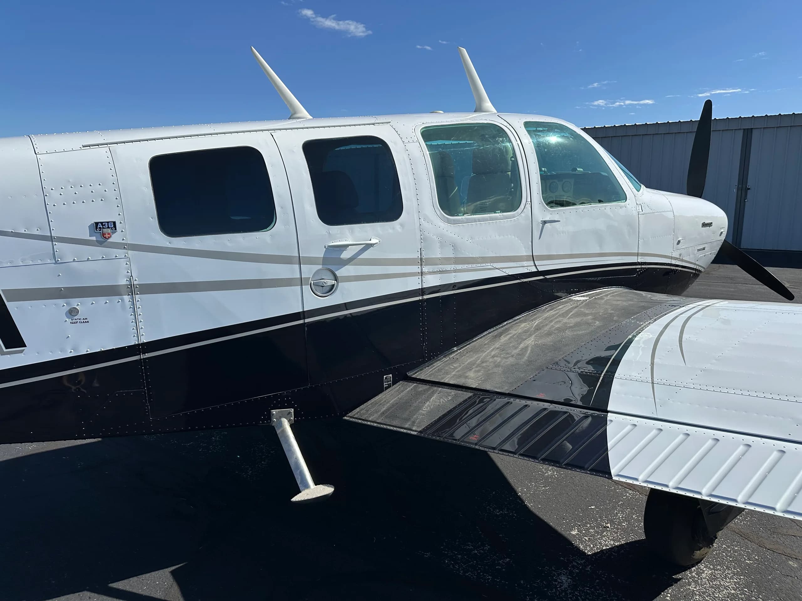 A close-up of the side of a Beechcraft Bonanza aircraft with a white and black paint scheme.
