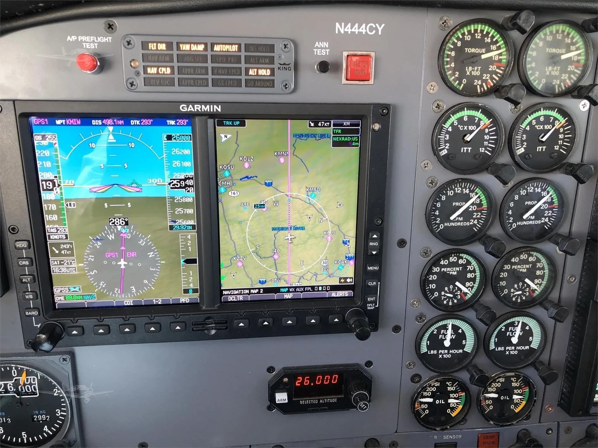 A close-up view of an aircraft's instrument panel, featuring Garmin displays and analog gauges, with the tail number N444CY visible above.