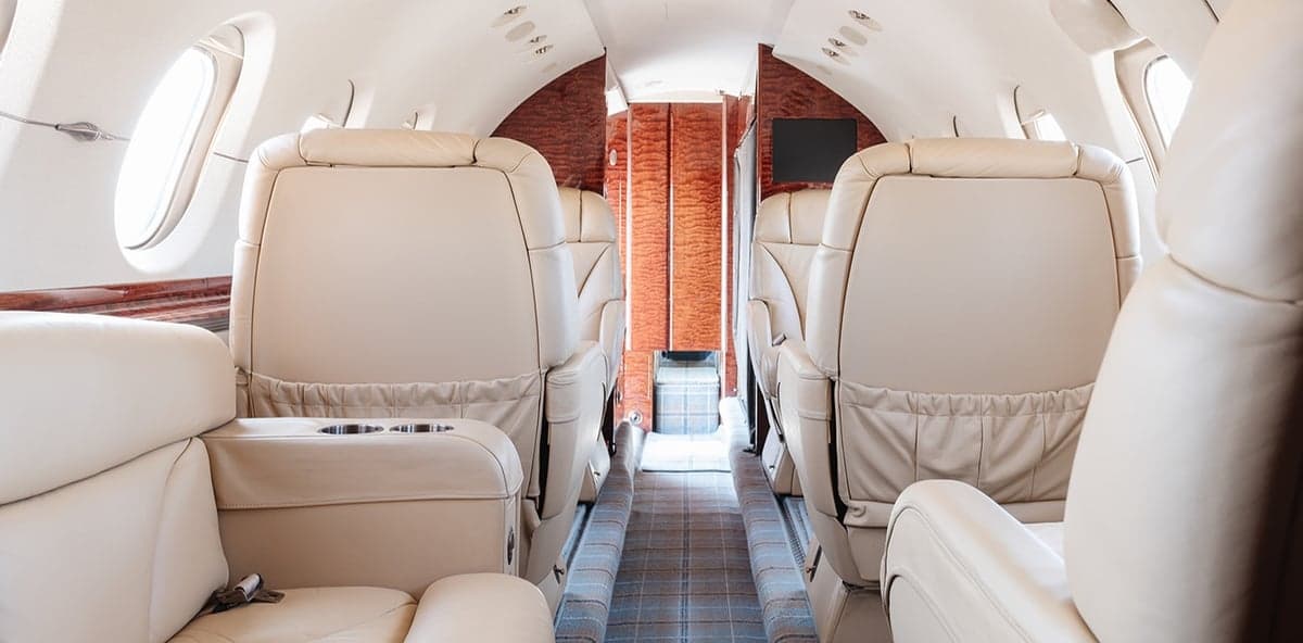 View of the aircraft's interior with cream-colored leather seats and wood paneling.