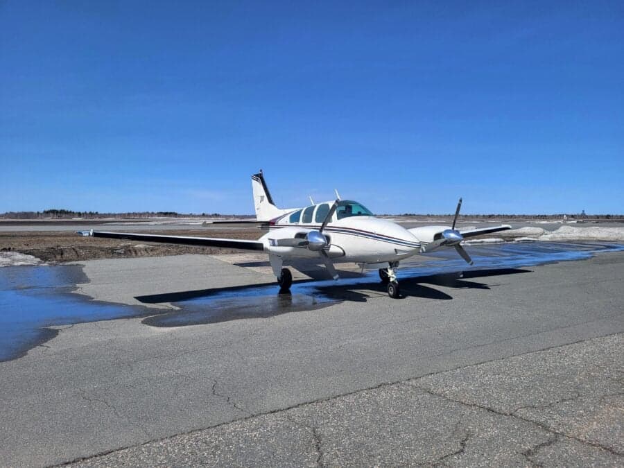 A Beechcraft Baron sits on the tarmac on a sunny day.