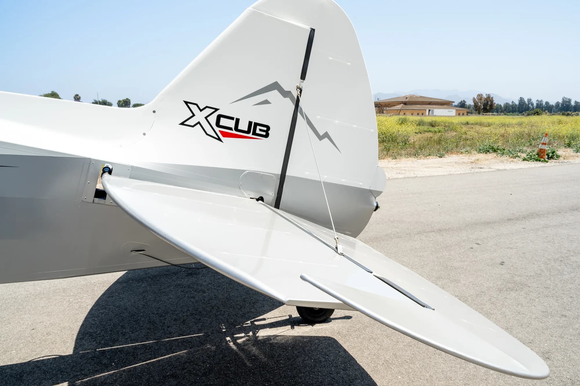 Close up of the tail and rudder of a white and gray CubCrafters XCub aircraft.