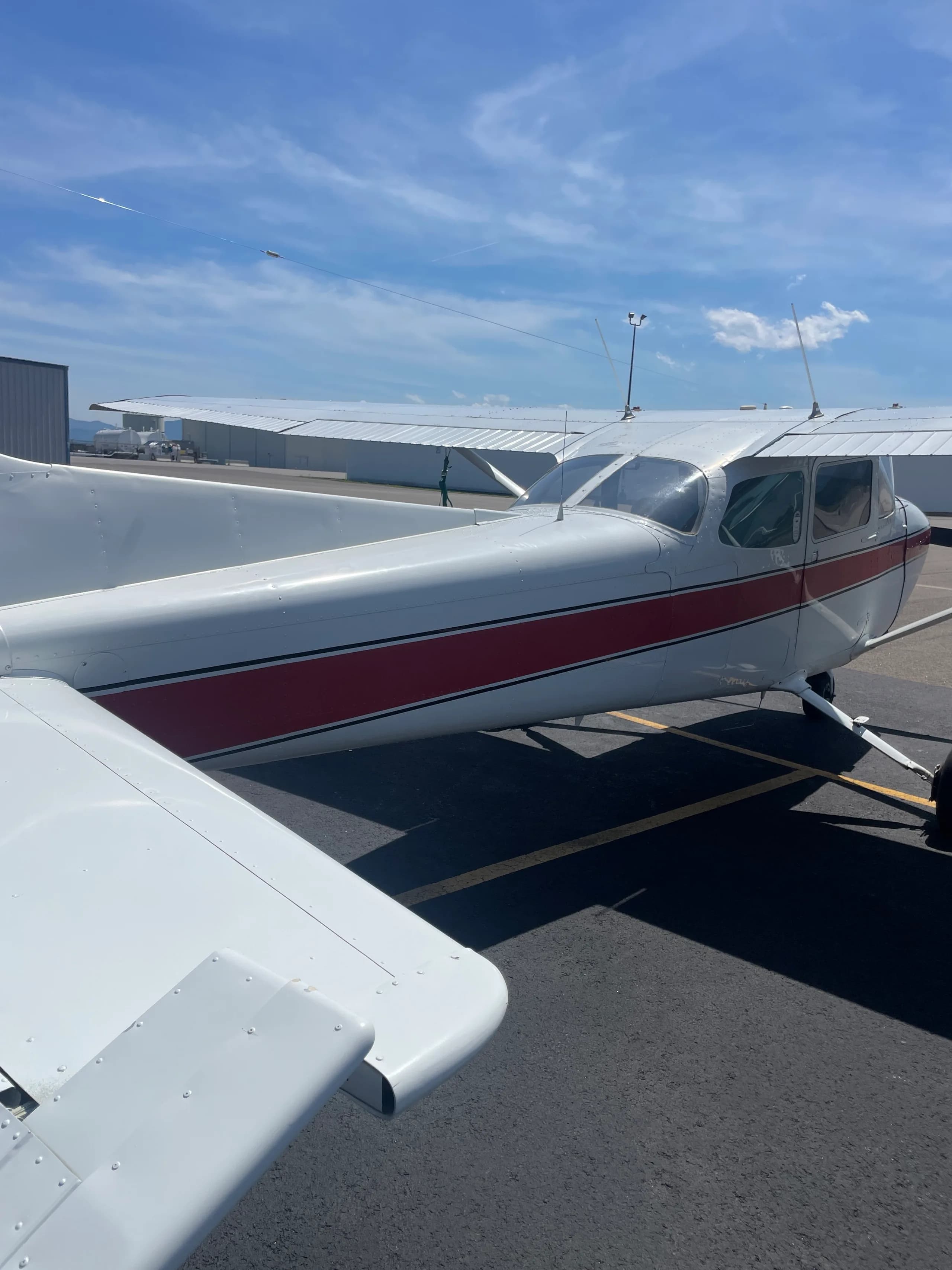 A rear-side view of the white and red Cessna 172, registration N733EN, parked on an asphalt ramp.