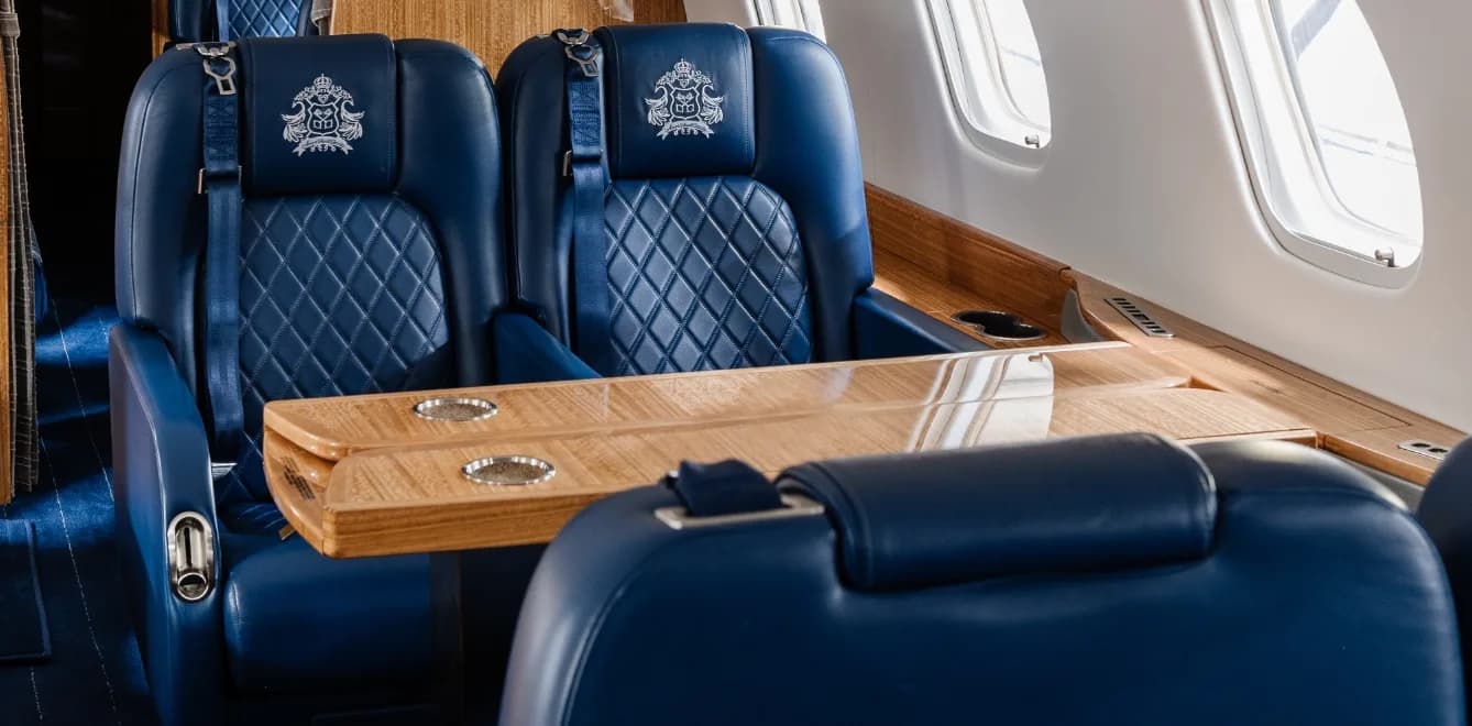 Close-up of blue leather aircraft seats with a wooden table between them.