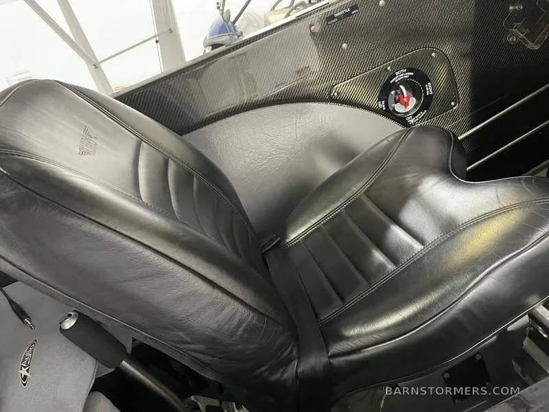 A black leather pilot's seat with a seatbelt in the interior of a CubCrafters aircraft.