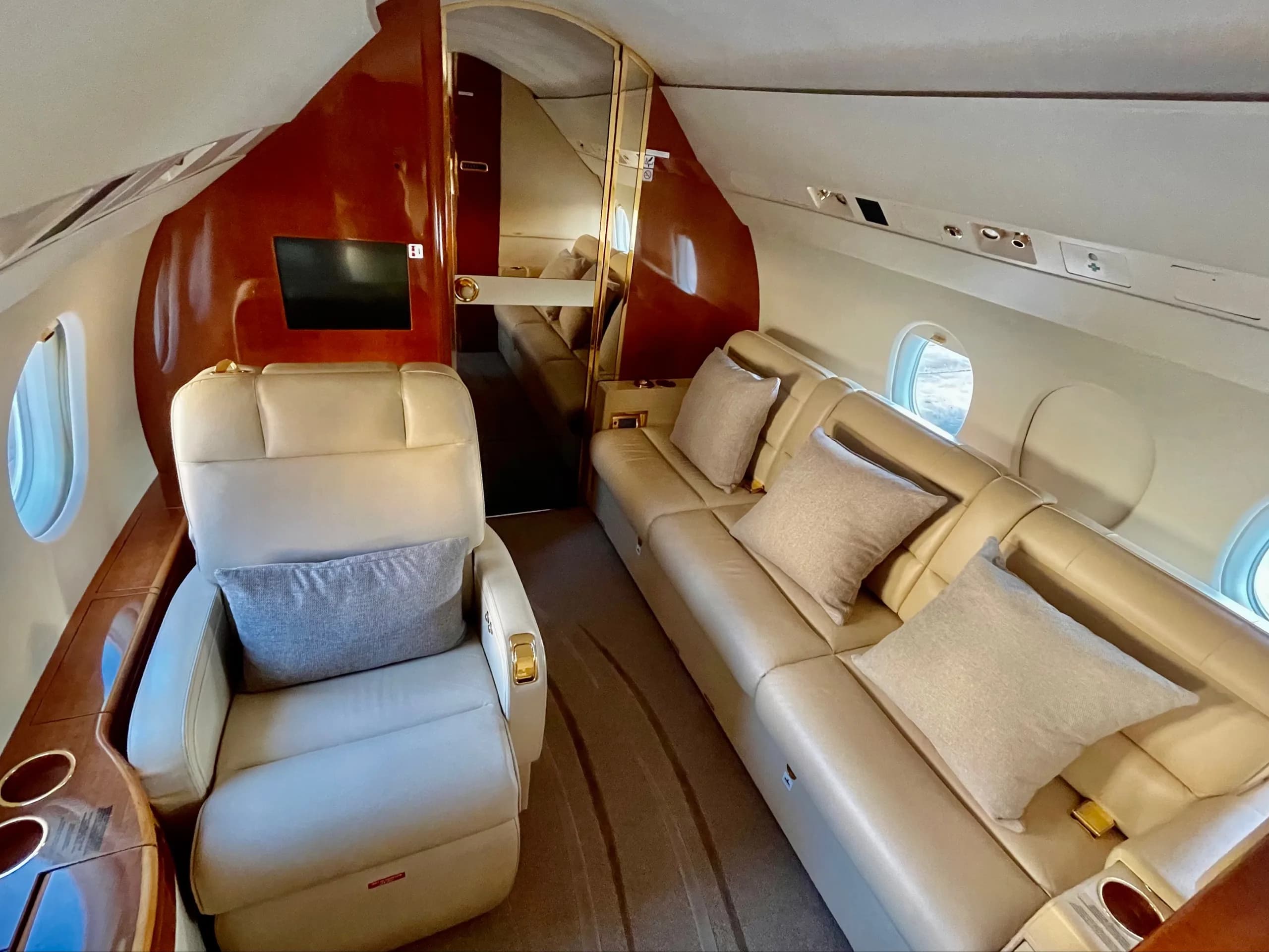 View of the aircraft interior with cream-colored leather seats and a couch.