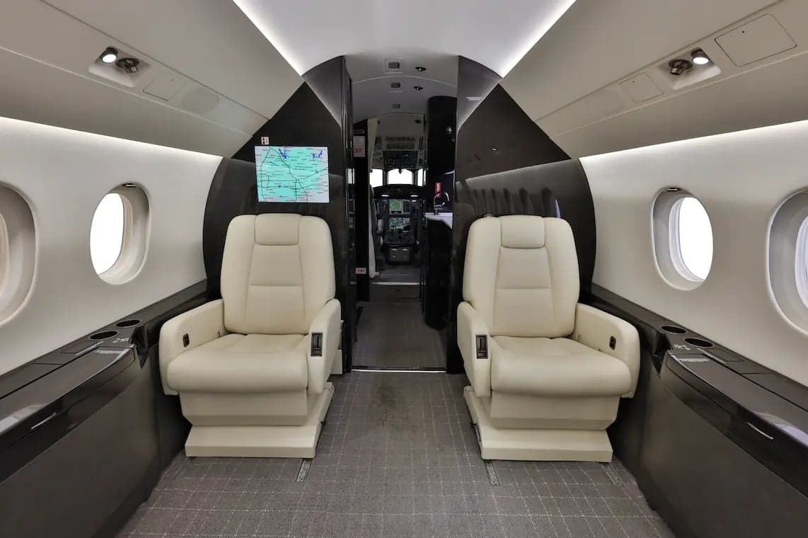 Two cream-colored seats facing each other in the aircraft cabin.