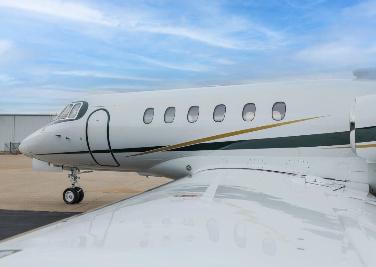 Close up of the front of a Hawker 800XP with a white and gold paint scheme.