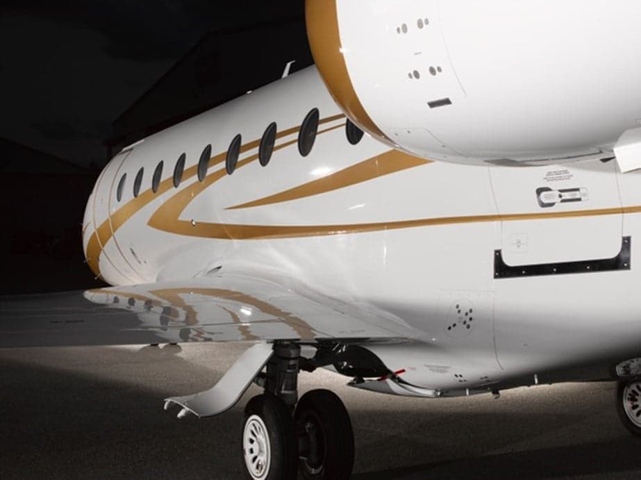 Close-up of the side of a white and gold aircraft, showing the wing and landing gear.
