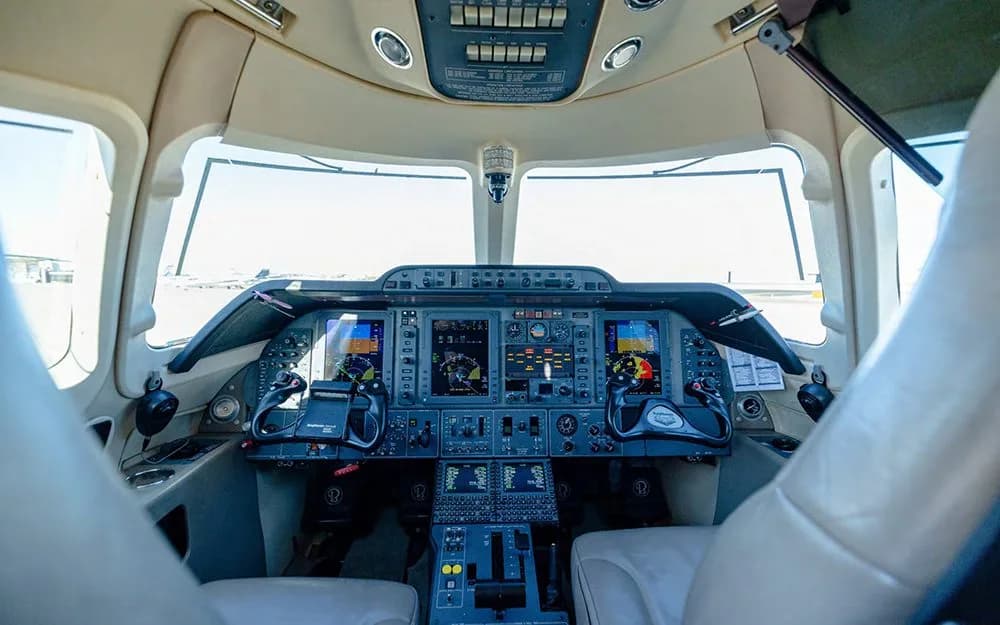 A wide view of the aircraft's cockpit, featuring multiple digital displays and control yokes.