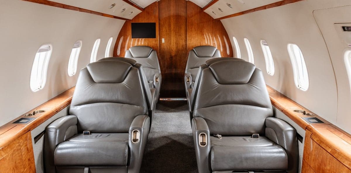 View of the cabin seats with wood trim and windows.