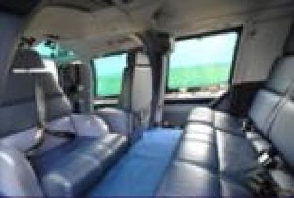 Interior view of the helicopter cabin with blue seats and carpet.