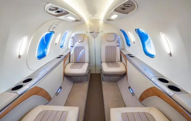 The luxurious interior cabin of a HondaJet Elite, showing two rows of beige leather seats facing each other with large oval windows.