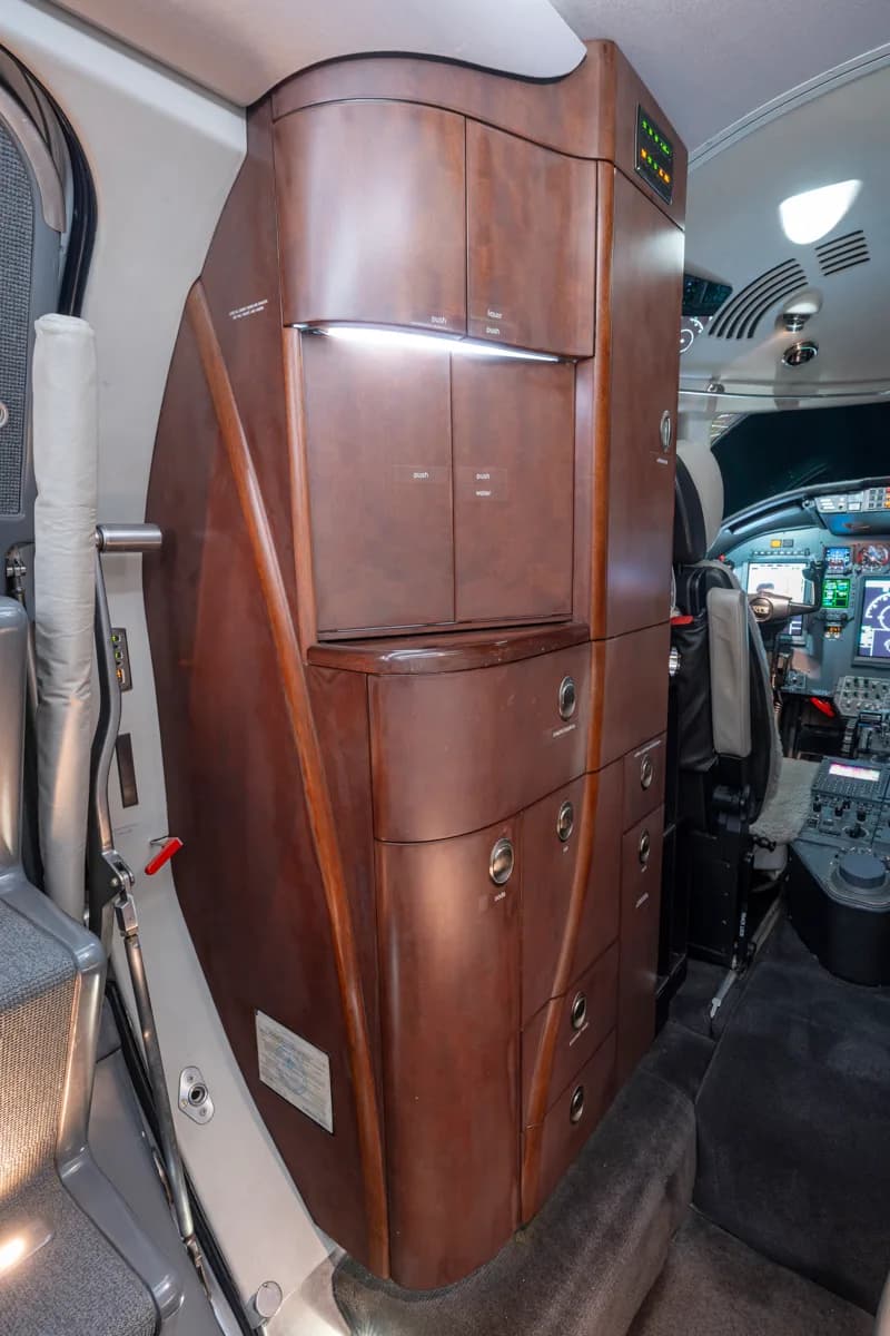 A view of the aircraft's interior, featuring a leather seat and a wooden cabinet with a sink.