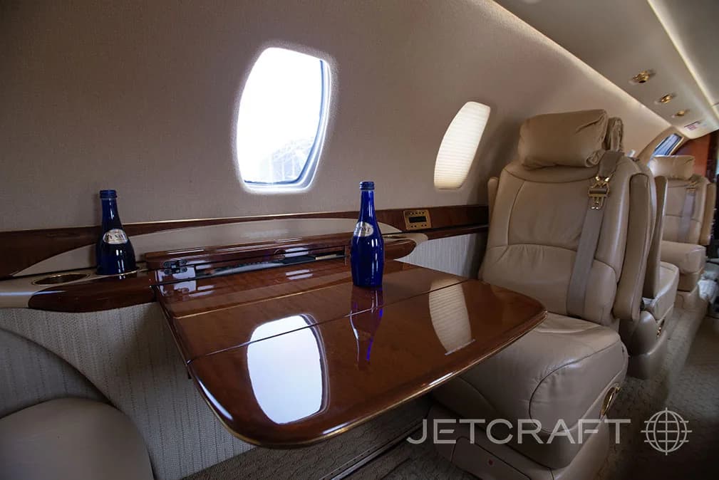 The interior of a jet with a fold-down table and leather seats.