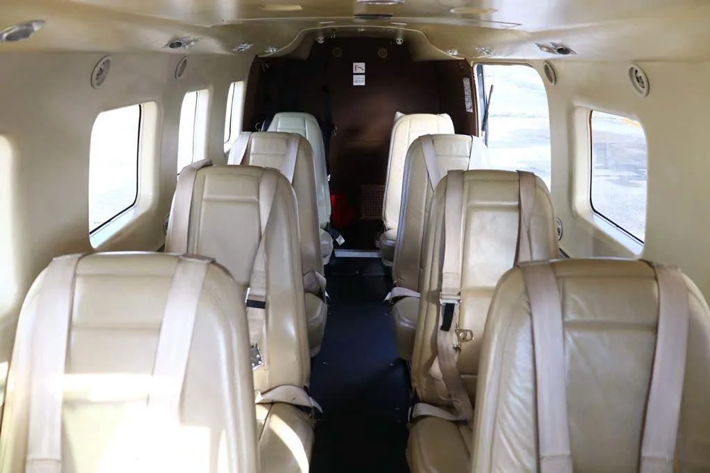The aircraft's interior cabin with multiple rows of light tan leather passenger seats.