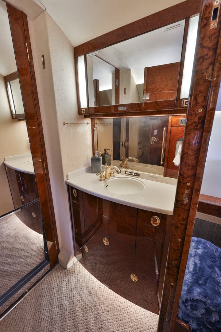 View of the aircraft lavatory with wood paneling and a mirror.