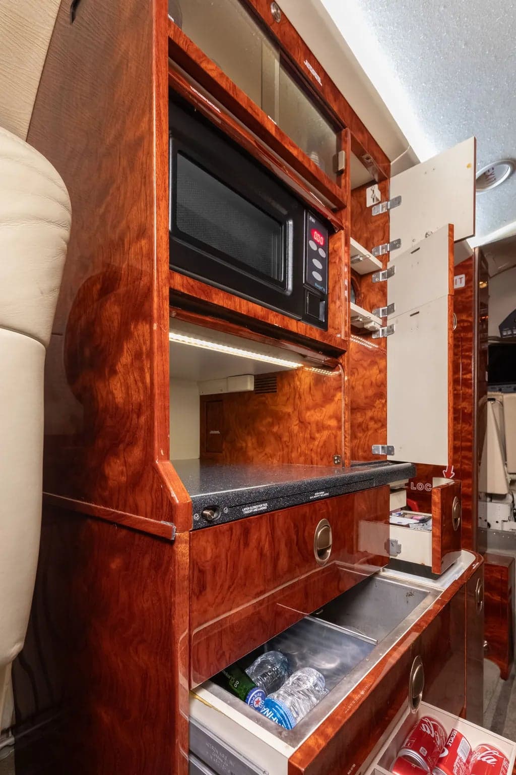 Interior view of the aircraft showing wood cabinetry with a microwave and beverage storage.