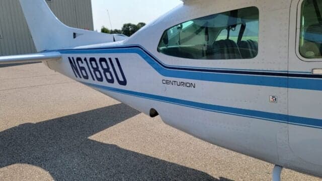 A Cessna Centurion aircraft with a blue and white paint scheme is parked on the tarmac.