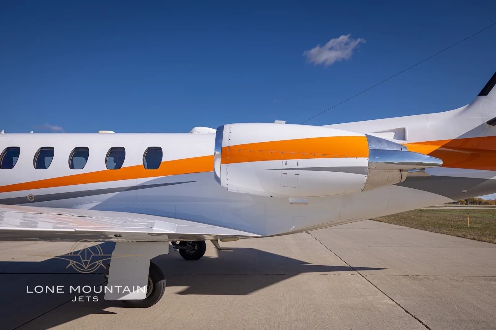 A close-up view of the engine and mid-fuselage of the Cessna Citation Bravo N589HH, showing the orange stripe.