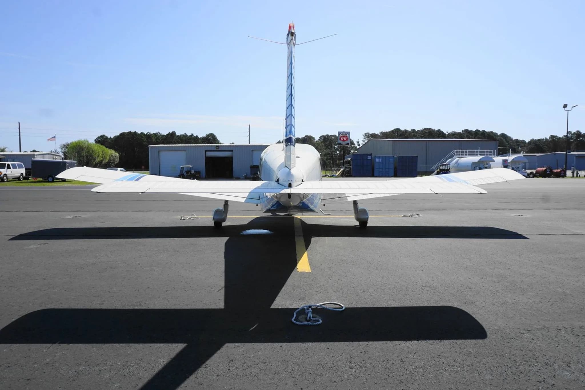 Direct rear view of the white N5527J aircraft with blue tail stripes on an airport tarmac.