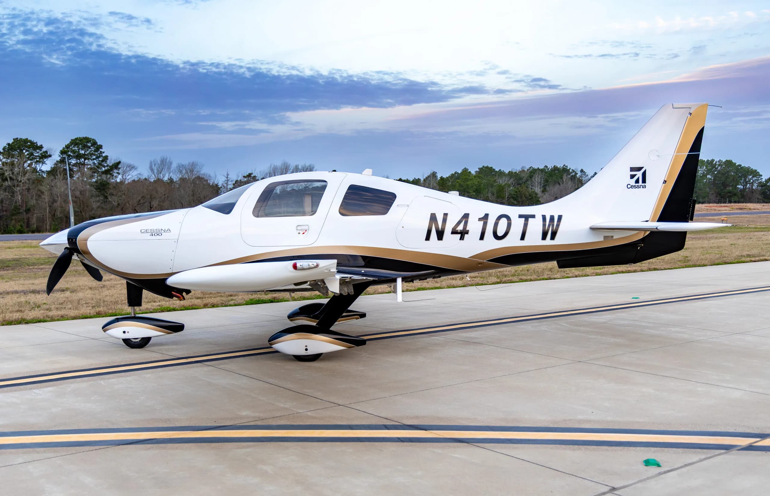 Cessna 400, registration N410TW, parked on the tarmac with a white and gold paint scheme.