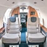 Close up of the aircraft cabin with leather seat, wood trim, and window.