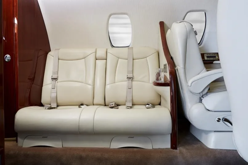 A view of the aircraft interior with cream-colored leather seats and a side table.