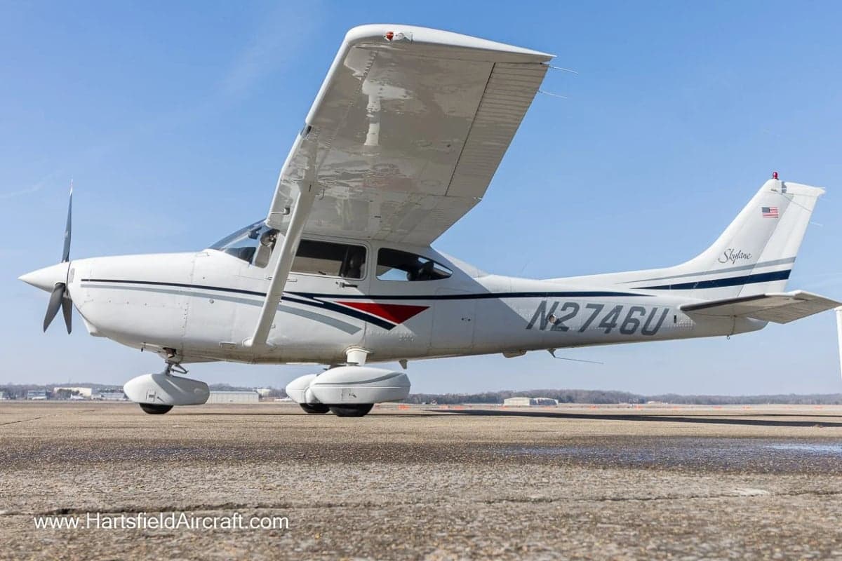 A Cessna Skylane aircraft with a white and gray paint scheme parked on the tarmac.