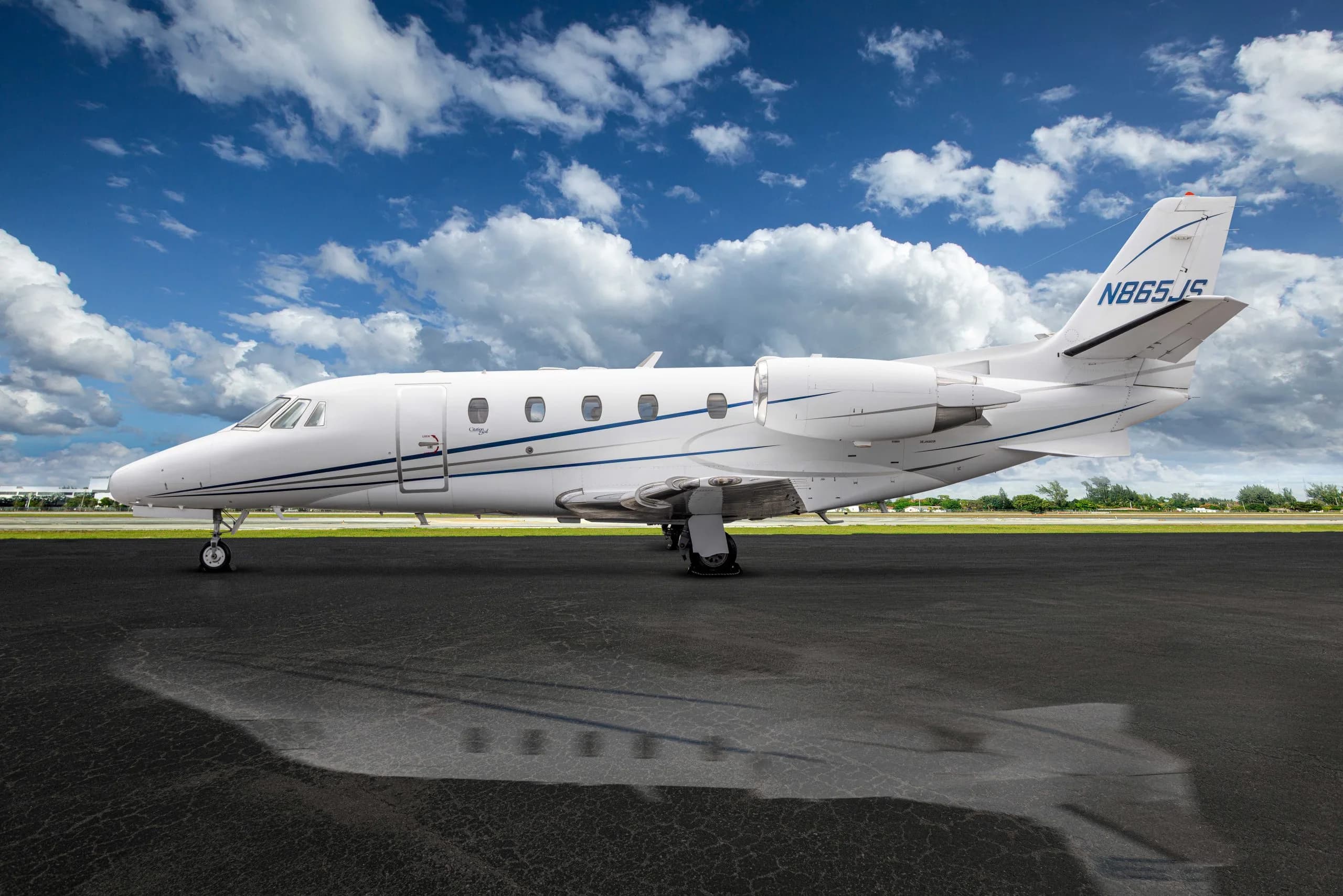 Side view of a white aircraft with blue stripes parked on the tarmac.