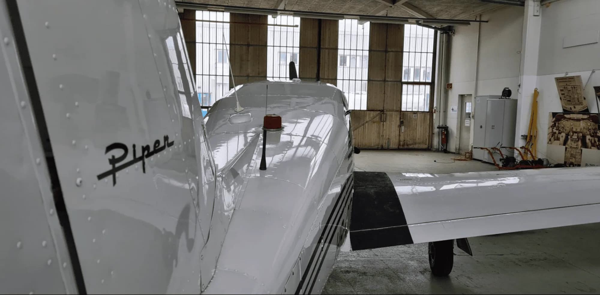 Close-up of the tail of a Piper Comanche 250 inside a hangar.