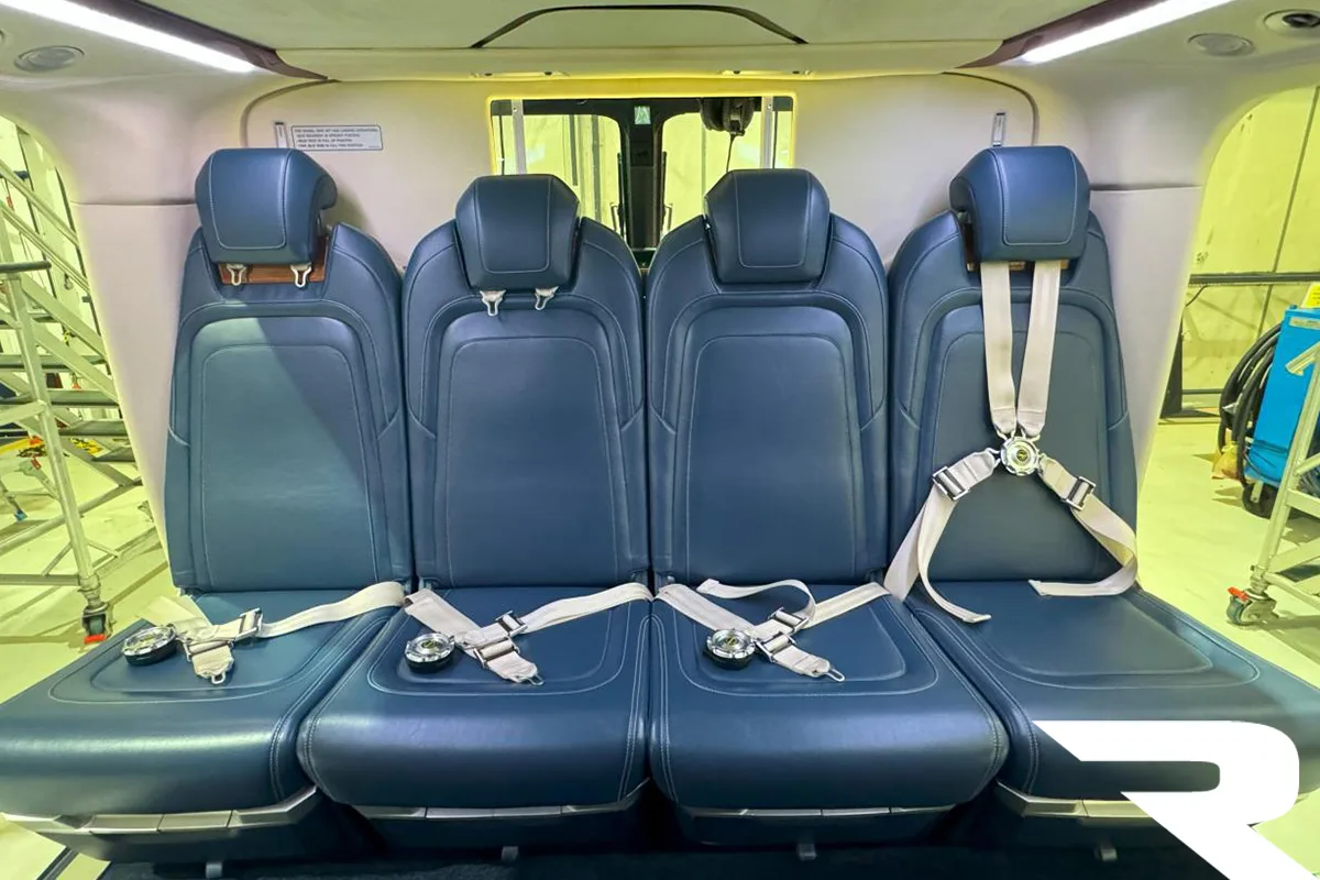 Rear-facing view of four blue leather passenger seats in a helicopter cabin.