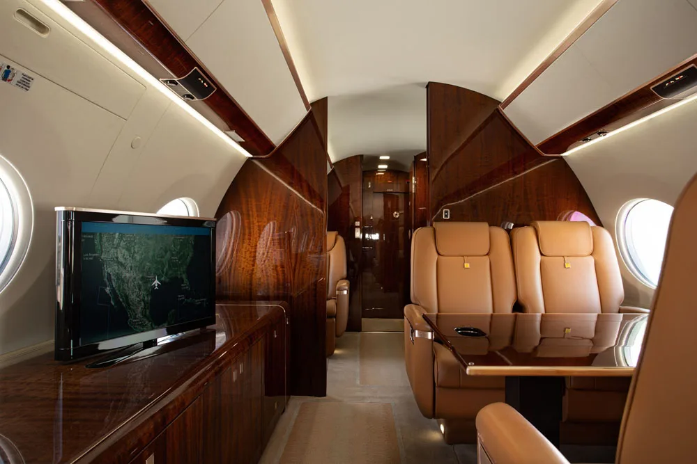 Aircraft cabin with leather seats and a TV monitor.