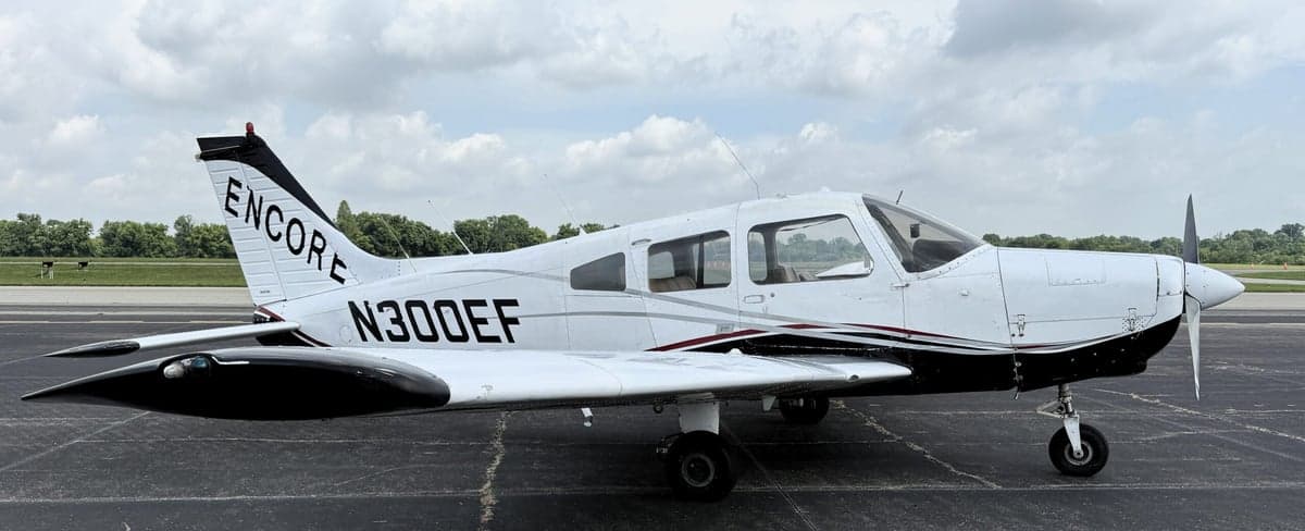 Side view of a white and black Piper PA-28-181 Archer II with registration N300EF on the tarmac.