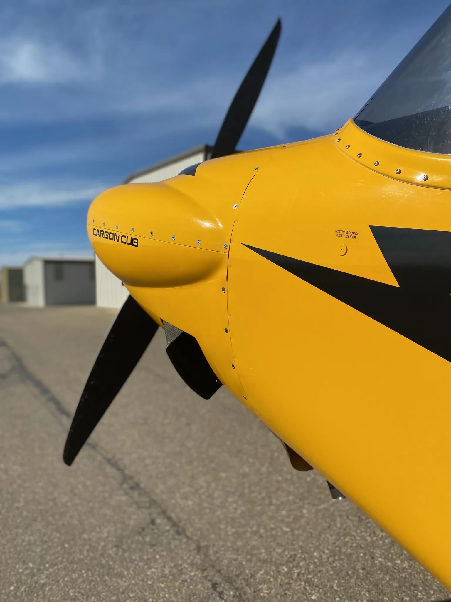 Close-up of the nose and propeller of a yellow Carbon Cub aircraft.