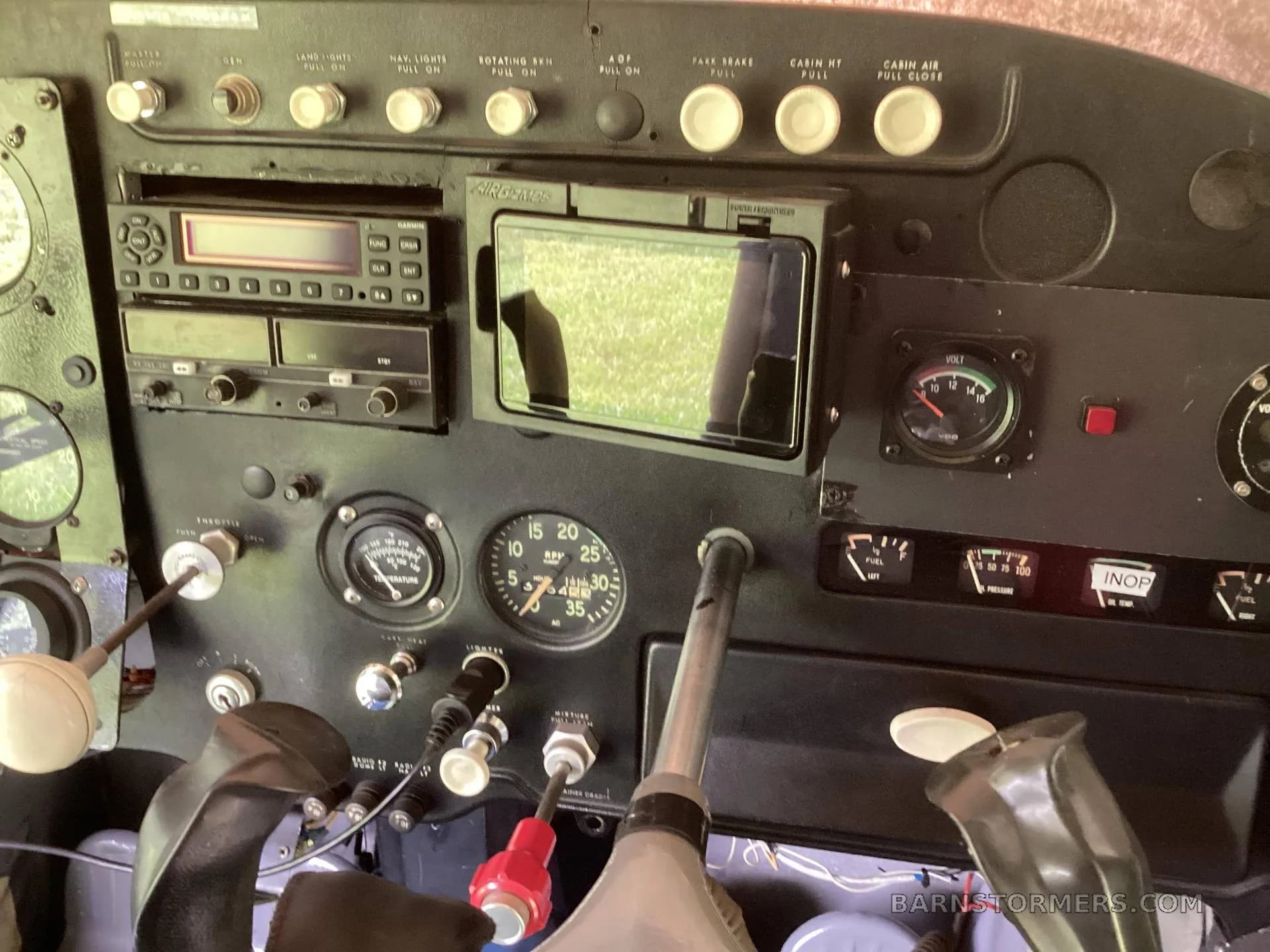 The black instrument panel of the aircraft, showing gauges, radios, and controls.