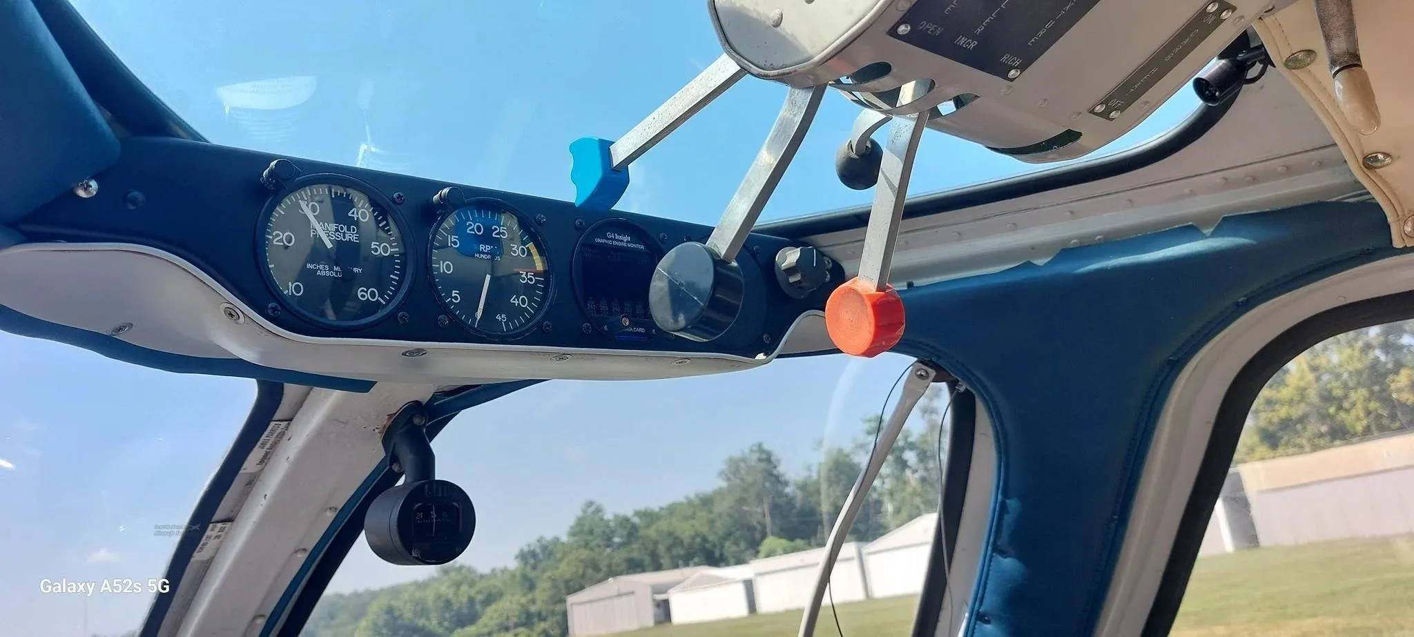 A wider view from the cockpit showing engine gauges, controls, and the exterior through the windshield.