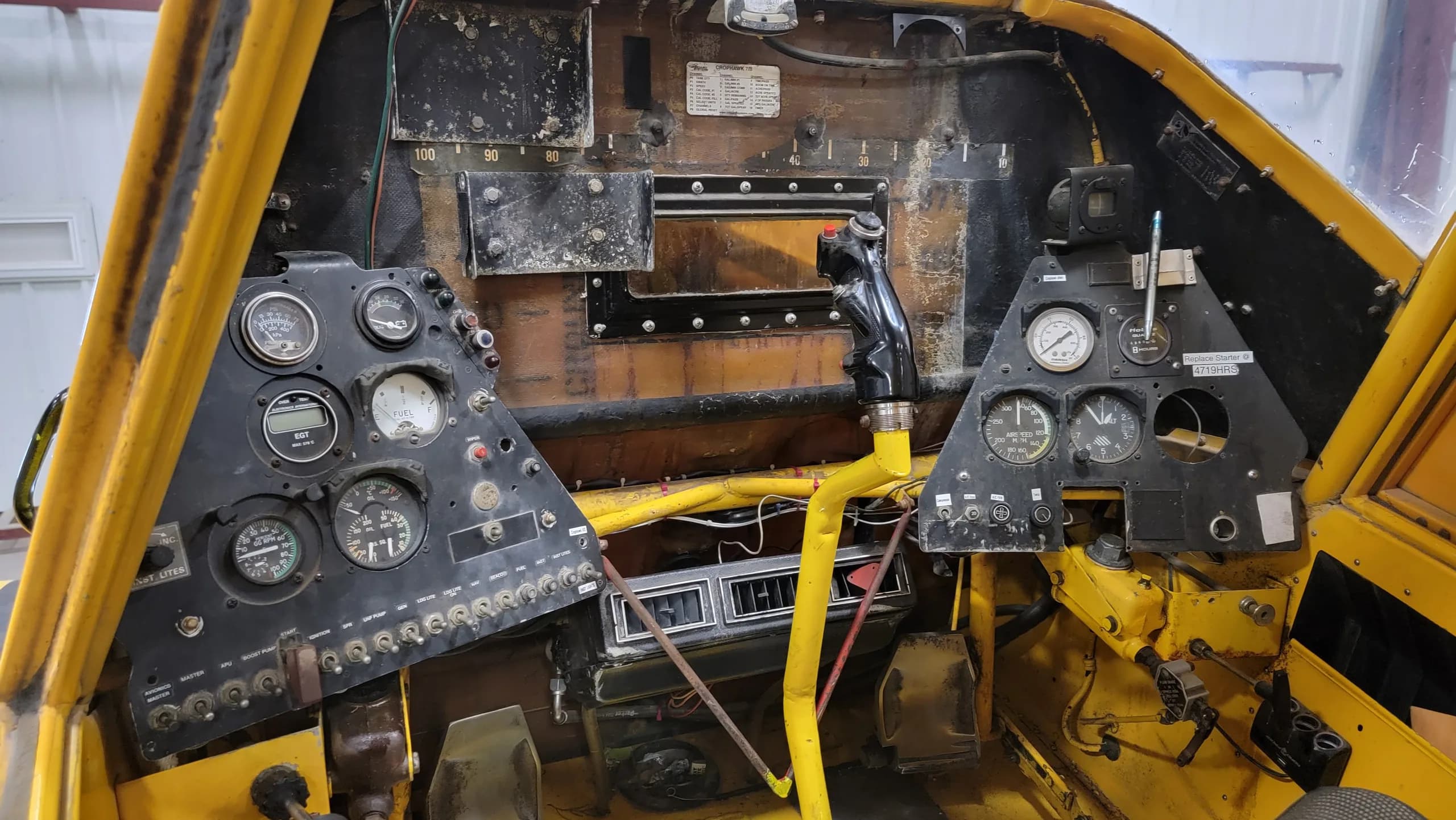 A detailed view of the yellow aircraft's instrument panel, showing various gauges, switches, and the control stick.