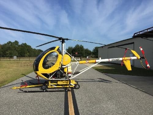 A yellow and black helicopter with tail number N9685F is parked on the tarmac.