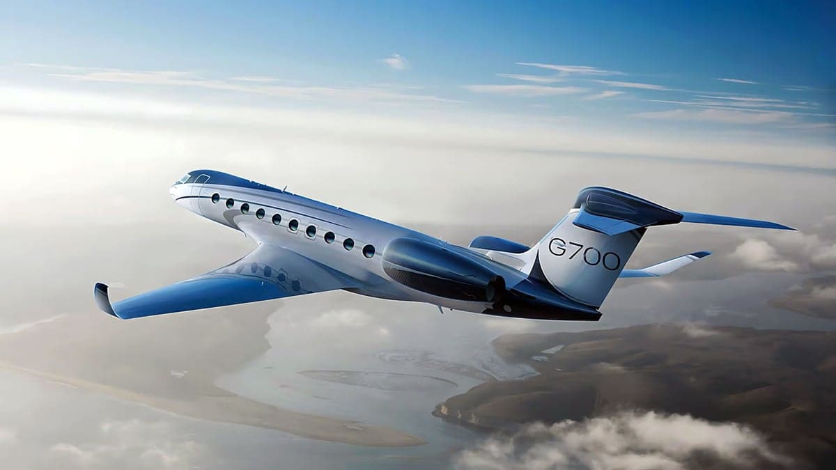 A Gulfstream G700 in flight over a coastal landscape.