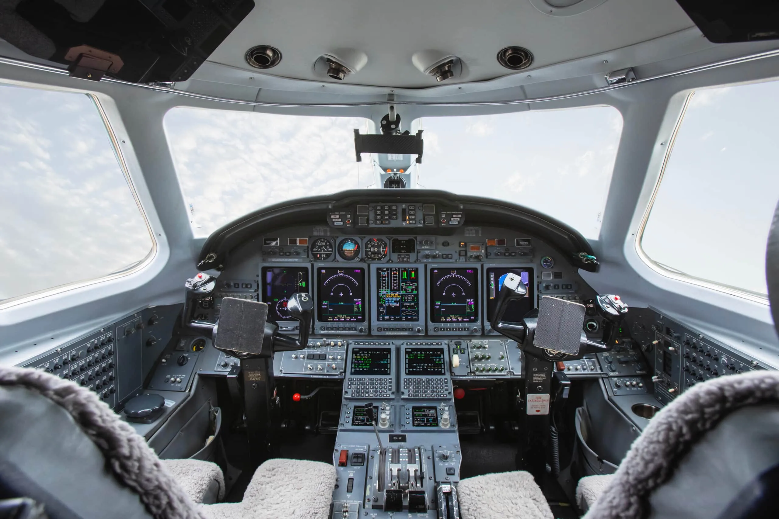 The cockpit of a private jet, featuring multiple digital displays and control panels.